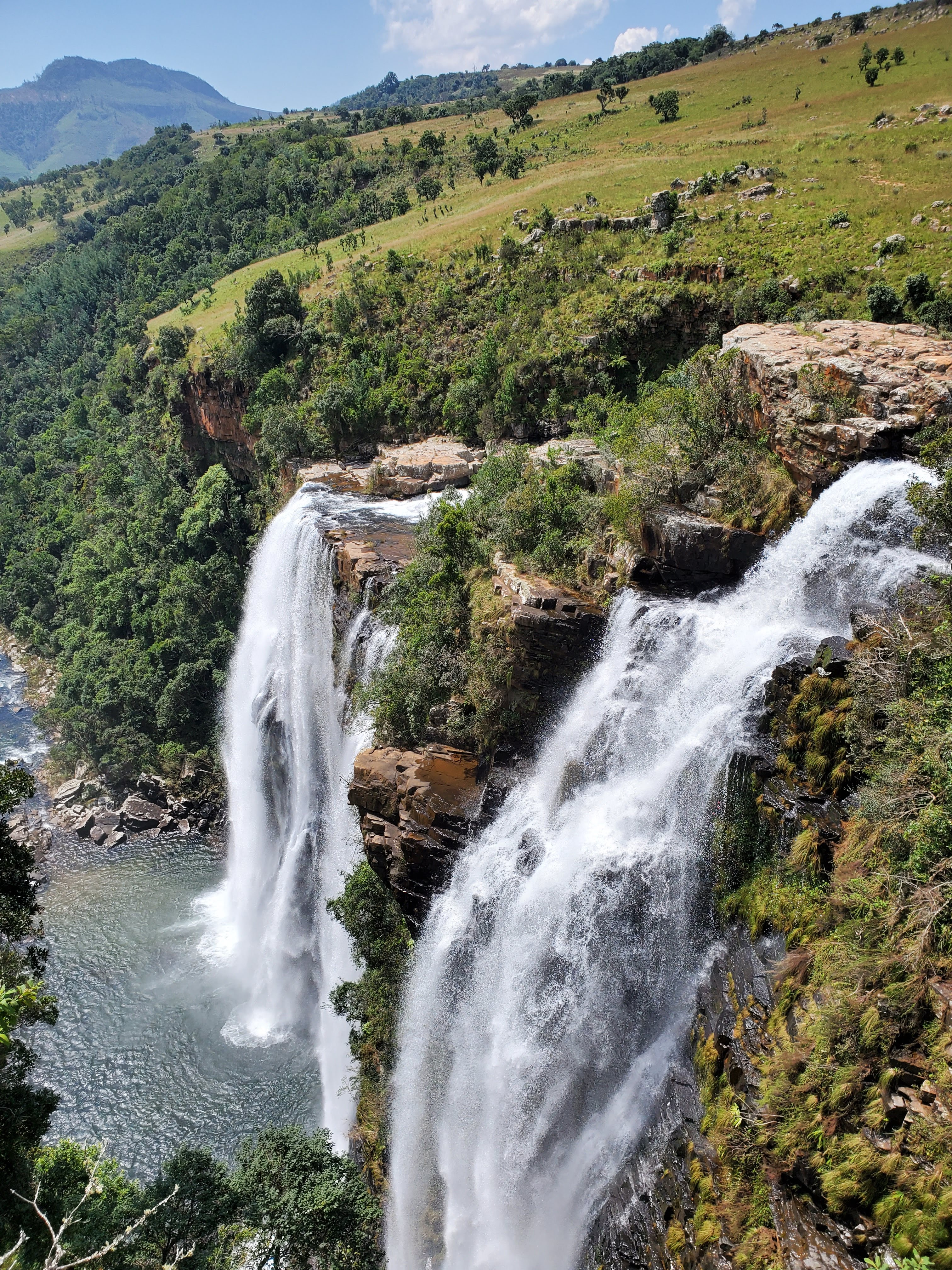 Two neighbouring waterfalls pour down into a turquoise pool in the lush green hills of Northern South Africa at Lisbon Falls