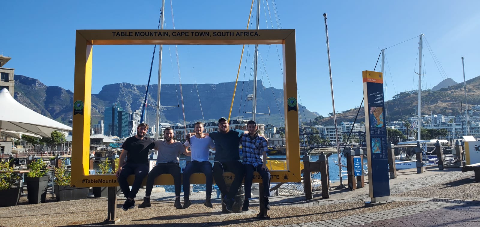 Five friends pose by a giant photo frame in Cape Town