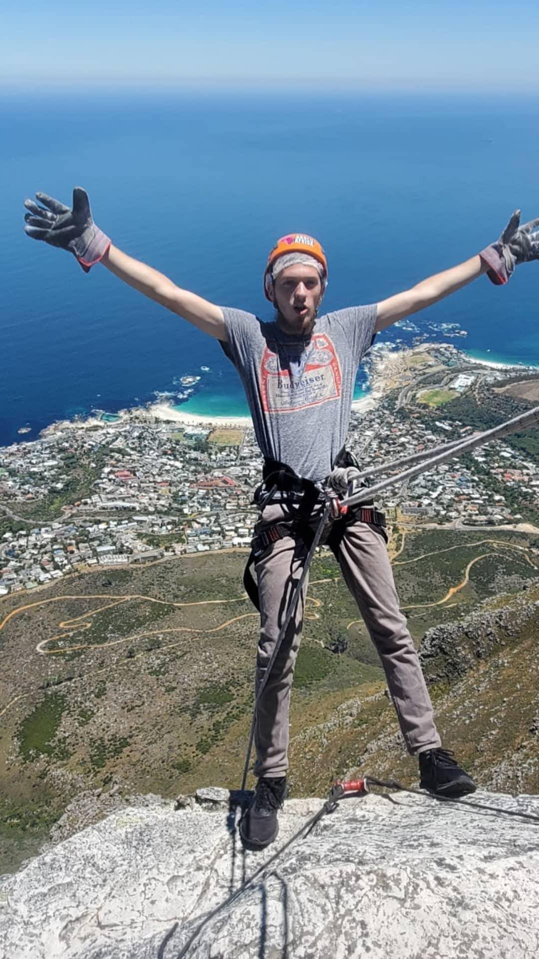 A man poses with his arms wide open while suspended over a huge cliff in Cape Town, while on an abseiling adventure!