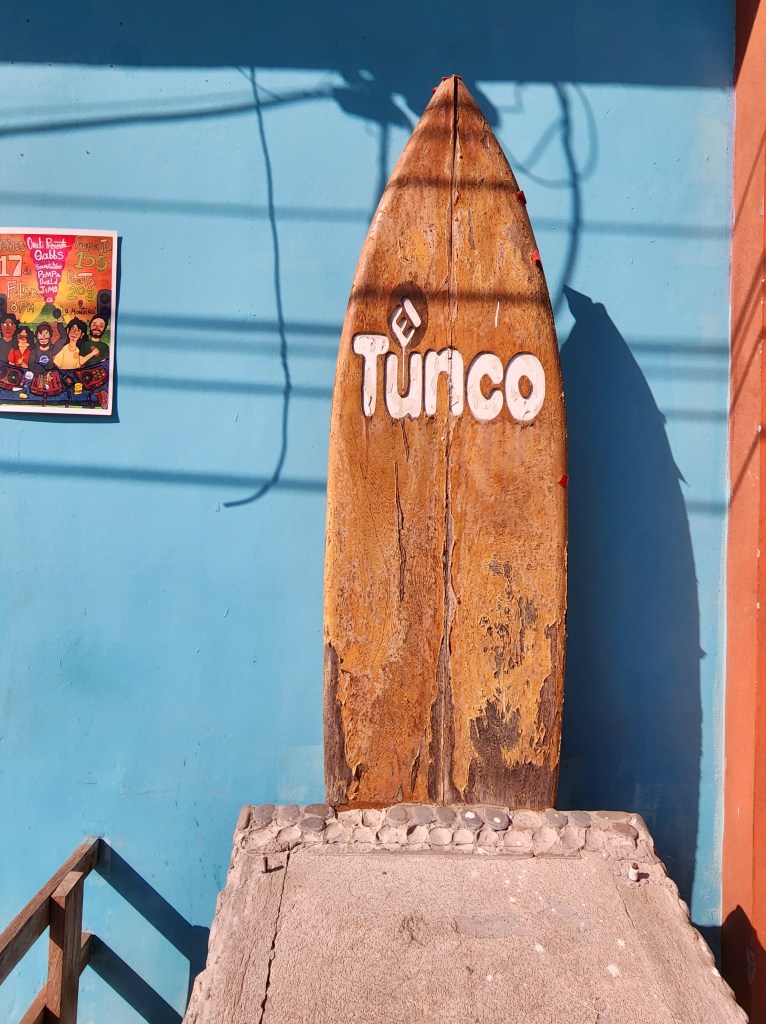 A wooden surf board with the words "El Tunco" carved into it welcomes you to the relaxed beach town