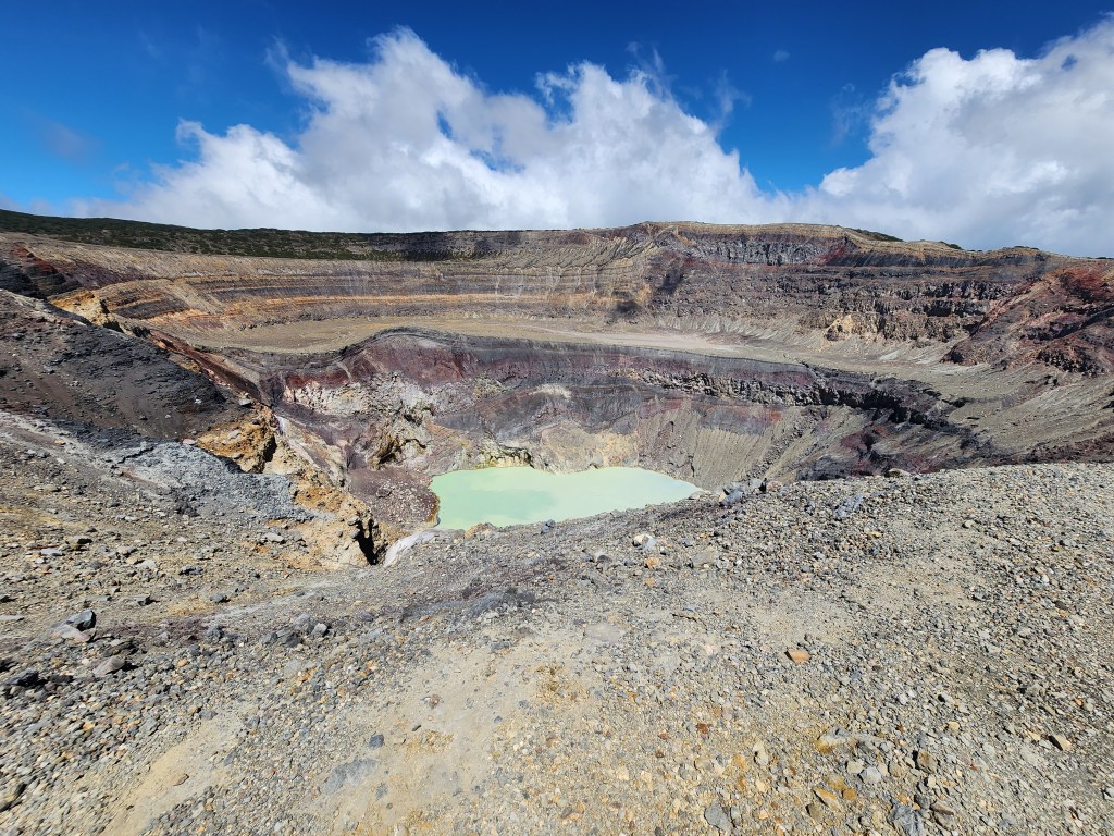 A large volcanic crater with a sulphuric lake that is a strong turquoise in the center