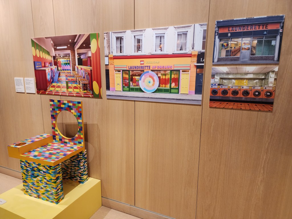 A colourful chair that looks like it's made out of lego (although it just painted like that) on display in an art gallery