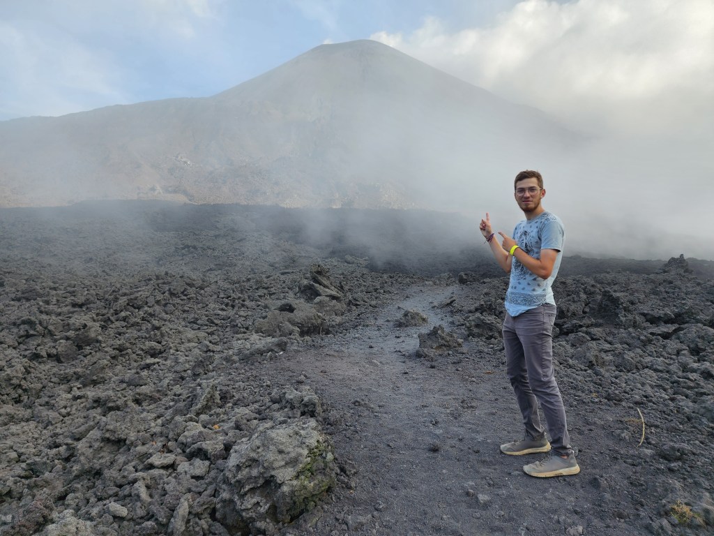 A man points at a smoke covered volcano in Guatemala