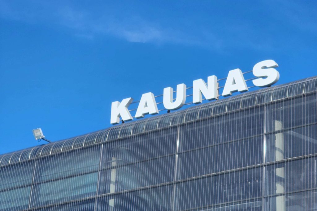 A large sign reads "KAUNAS" above an airport terminal