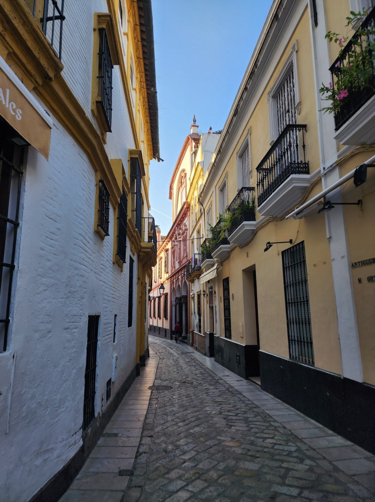 a cobblestone alley in Andalusia with houses brightly painted in white and yellow.
