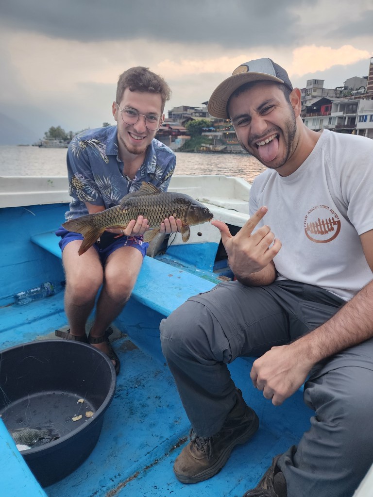 Two guys posing with fish they caught on a blue boat in Lake Atitlan
