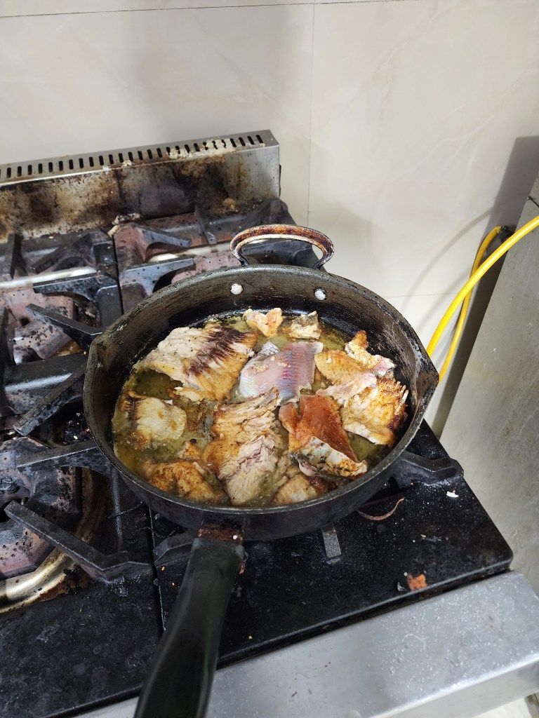 Fish being fried on a burnt stove.