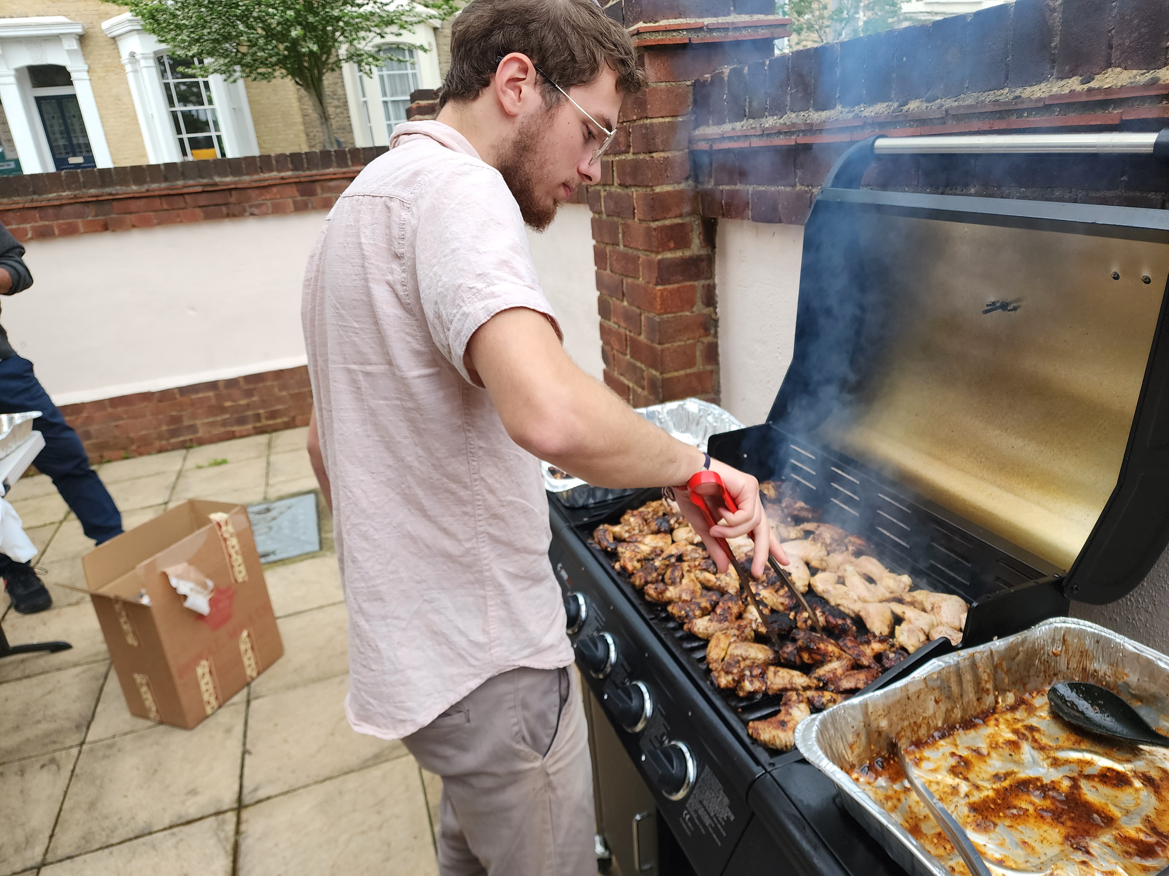 Young man flipping chicken wings on a grill