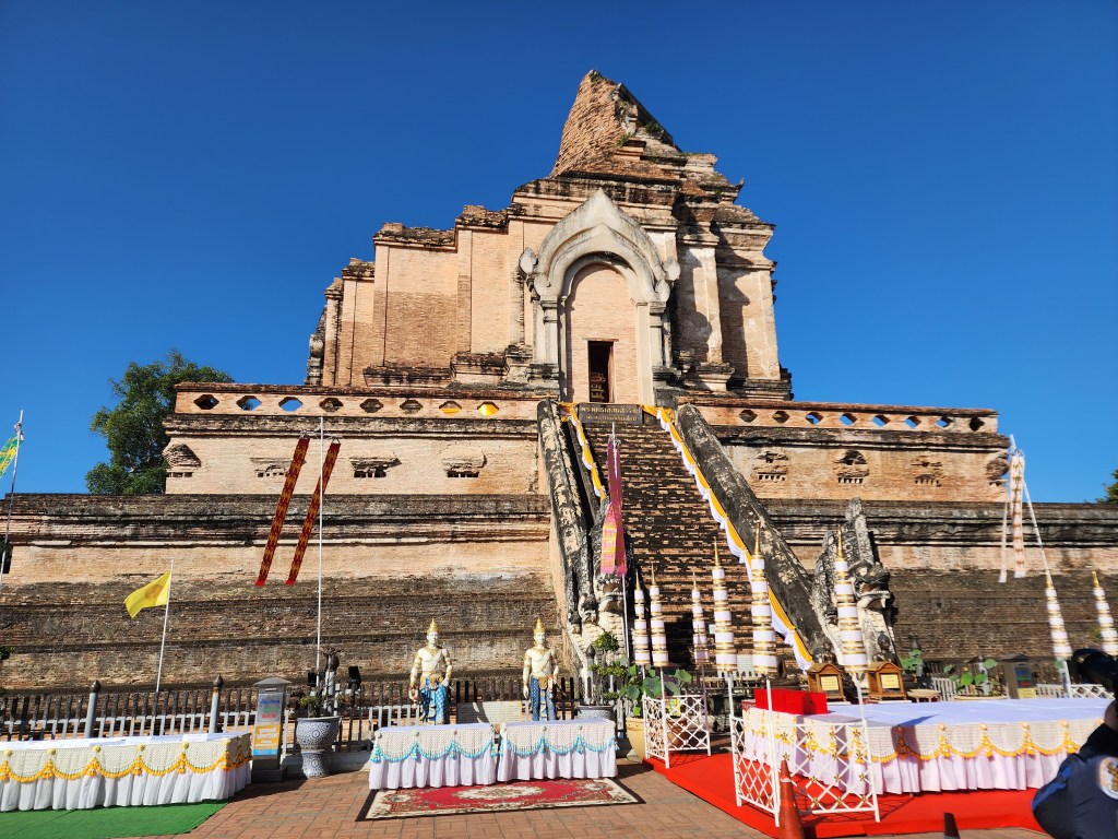 The ruins of a large temple structure with an intact stairway and broken sculptures of elephants.