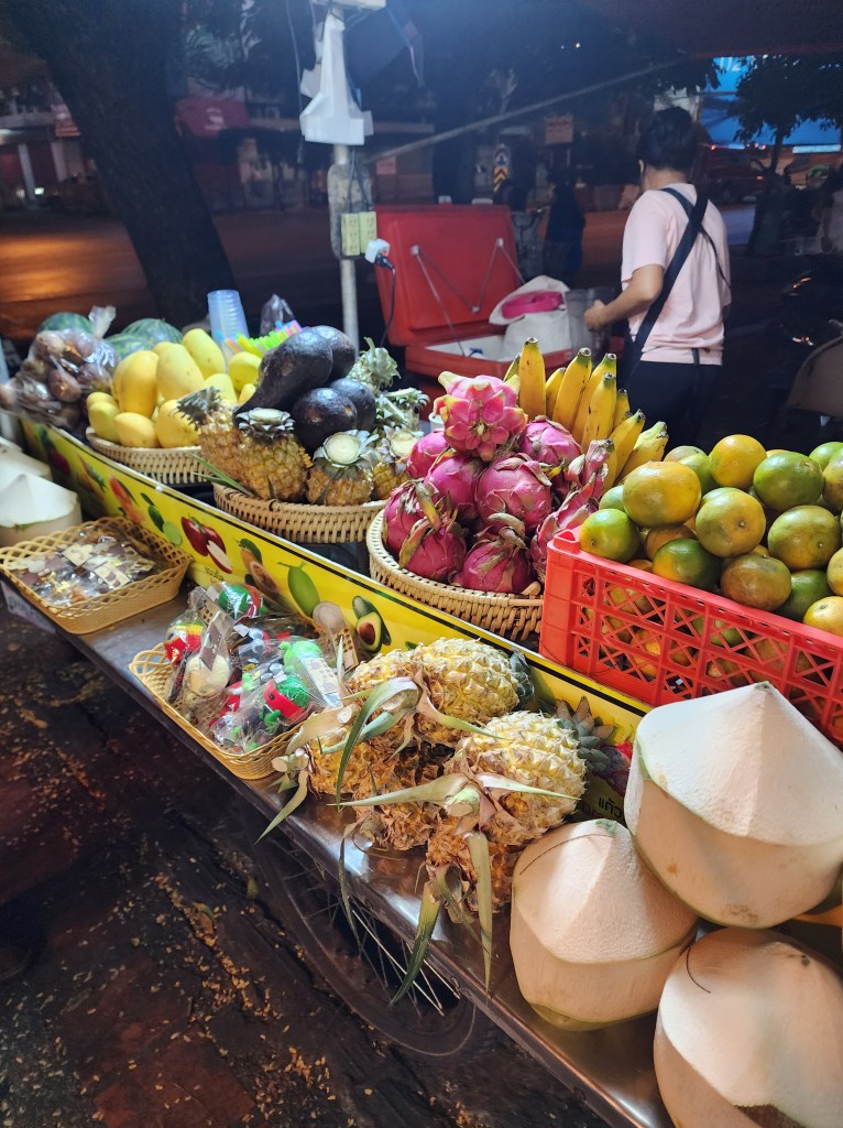 A smoothie stand with dragon fruit, coconut, lime, pineapples, lemons, passion fruit, and bananas.