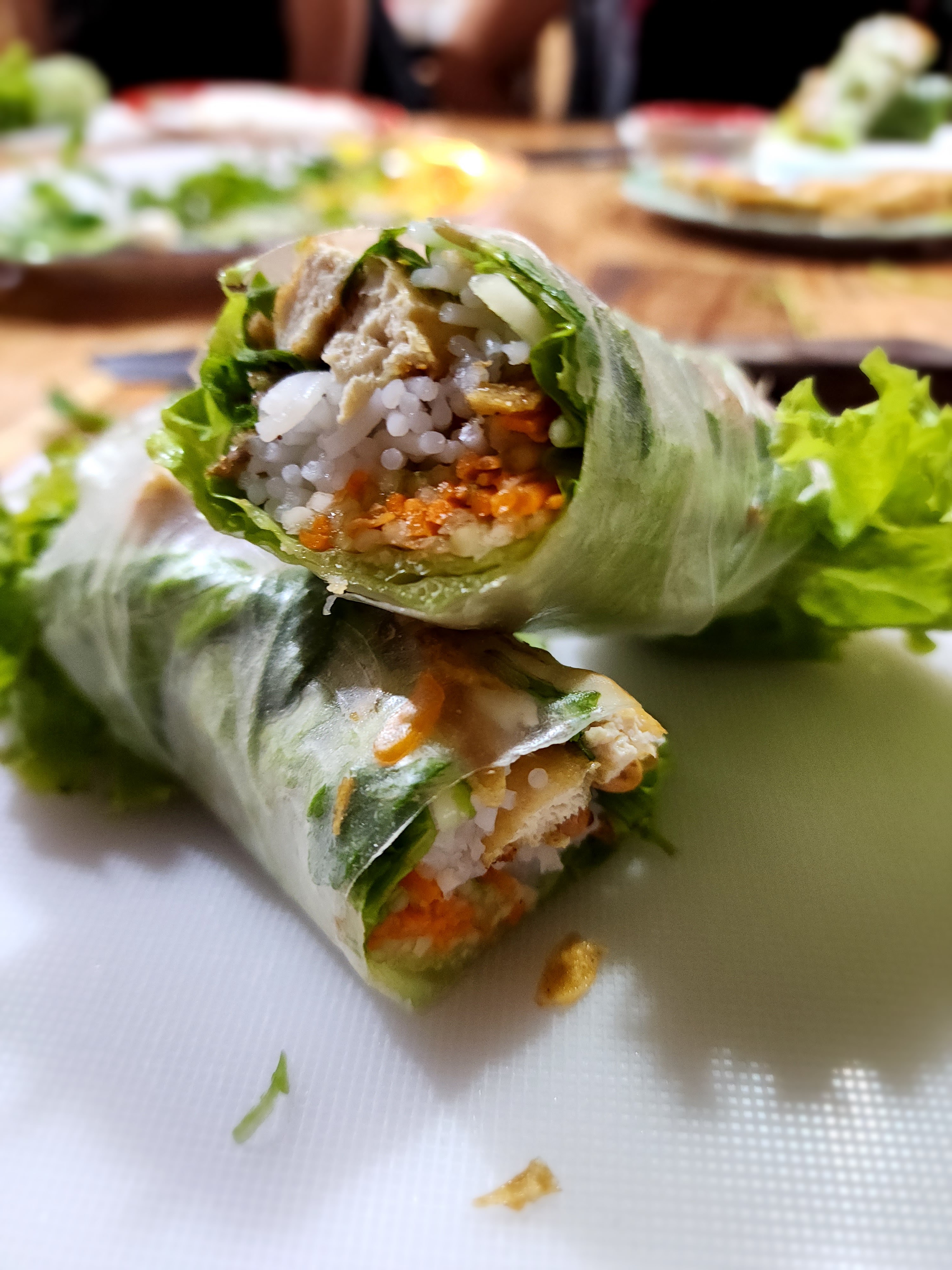 A close up view of a fresh Vietnamese spring role with tufu, lettuce, noodles, and much more tasty food.