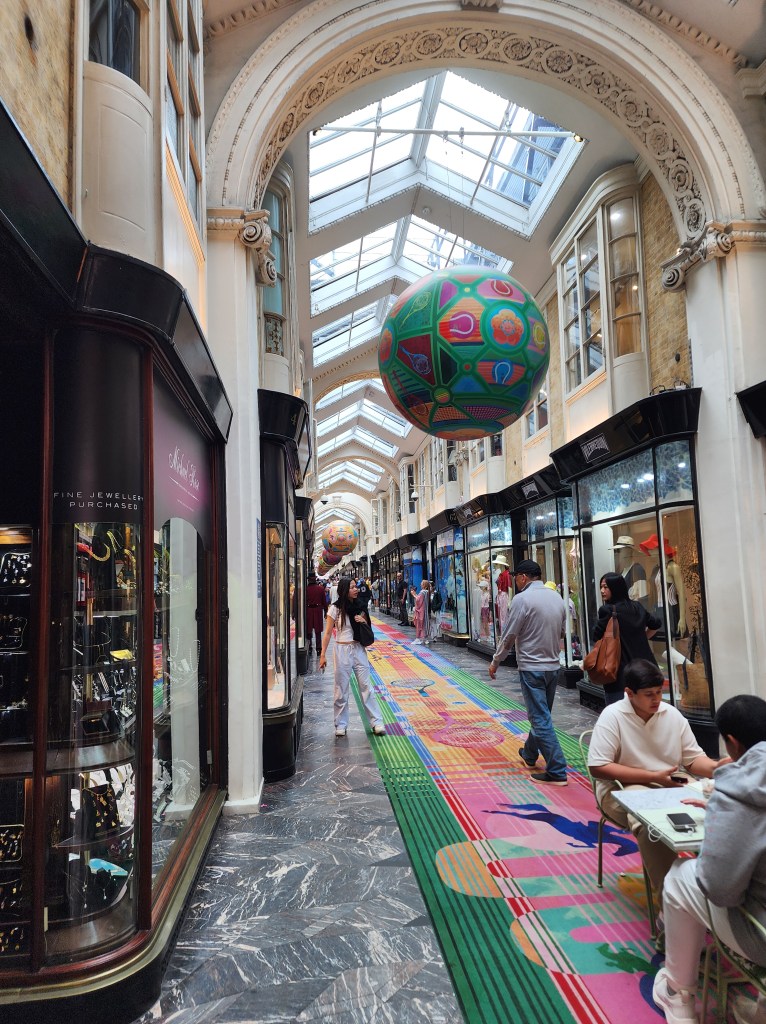 People walk on a vibrant, colourful rug in Burlington Arcade.