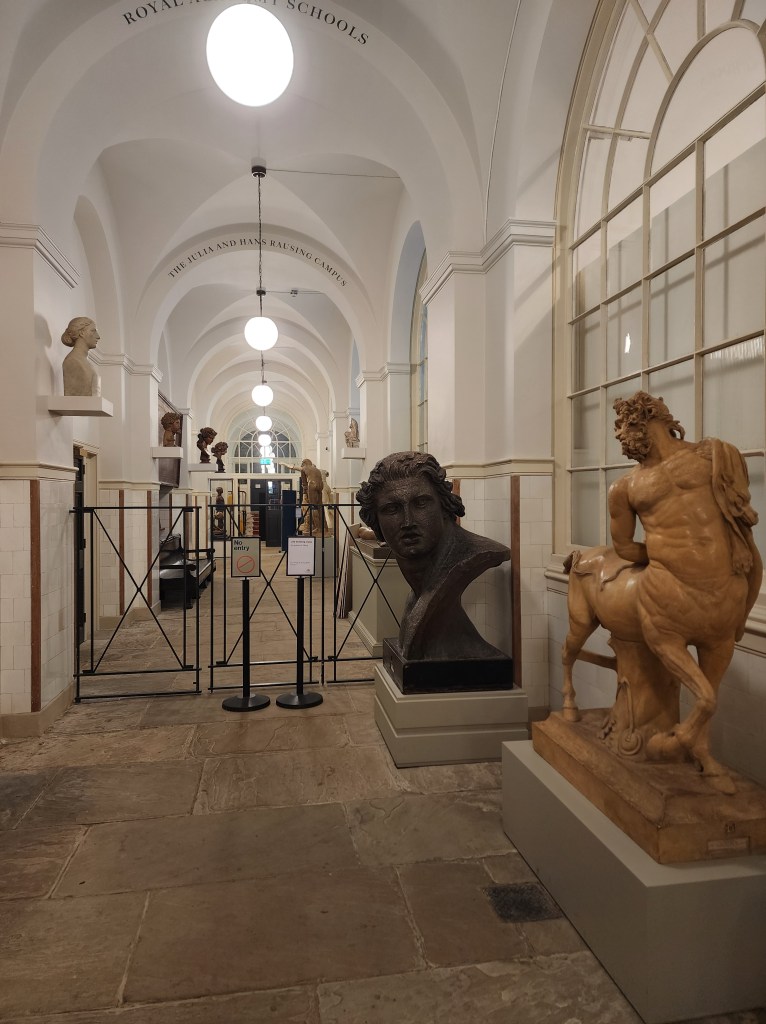 A hallway of stone sculptures in Burlington House