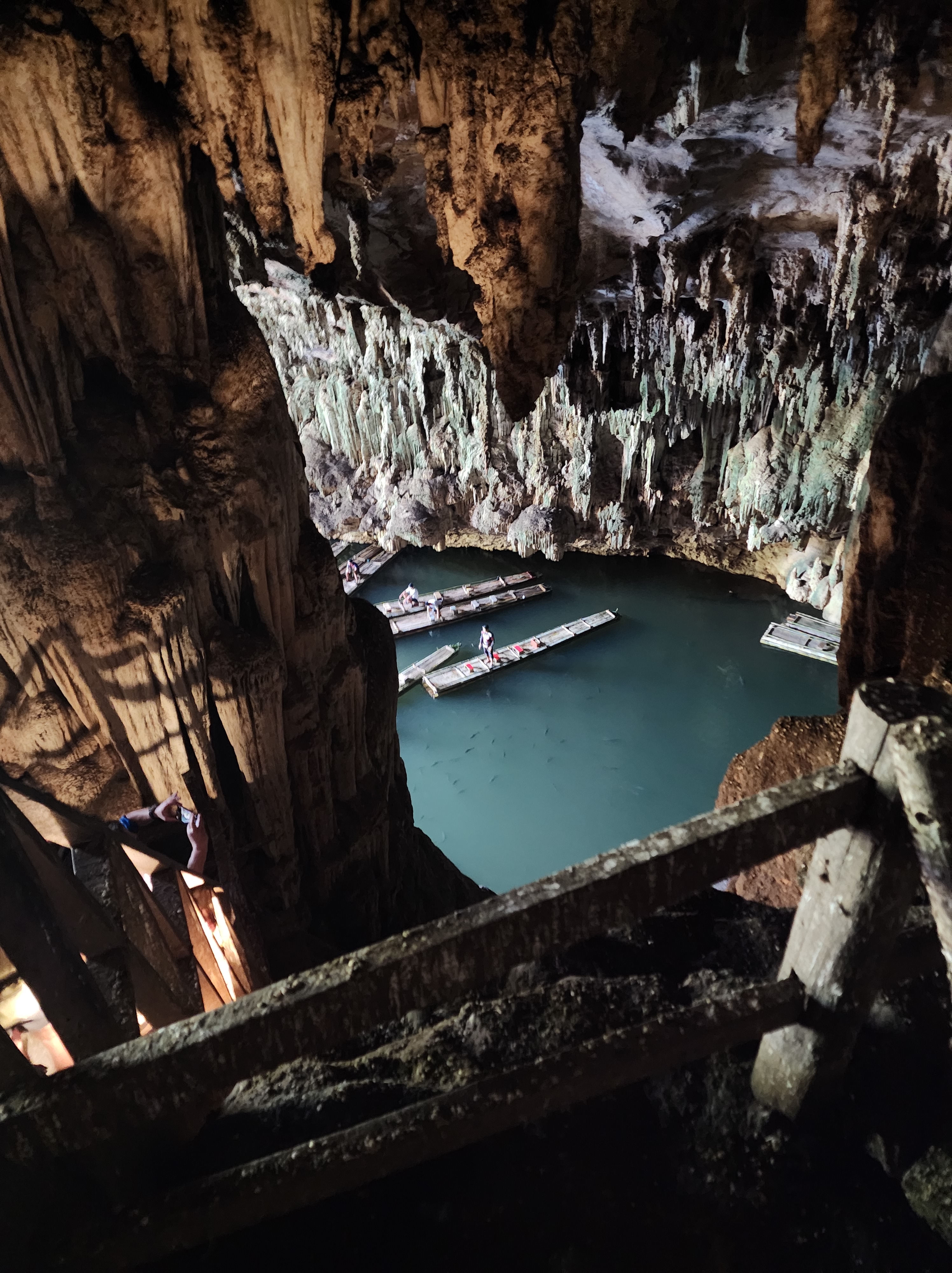 Bamboo rafts in the blue water at Tham Lod Cave. There are stalagmites and stalactites all around them.