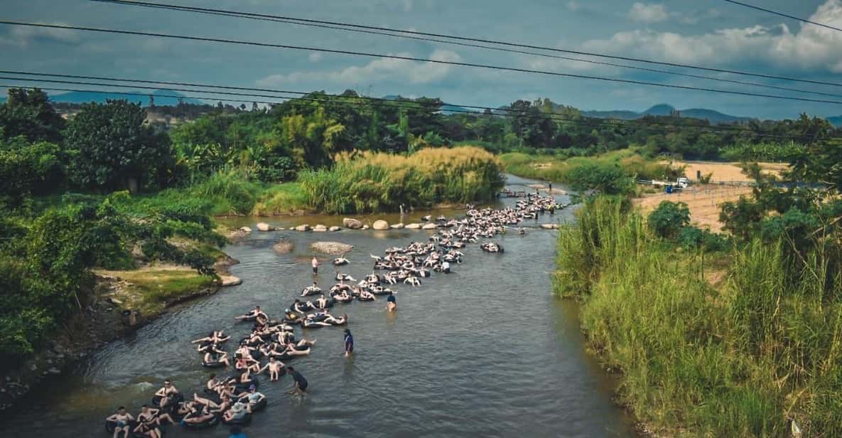People sitting in donut shaped rubber seats and floating down a river.