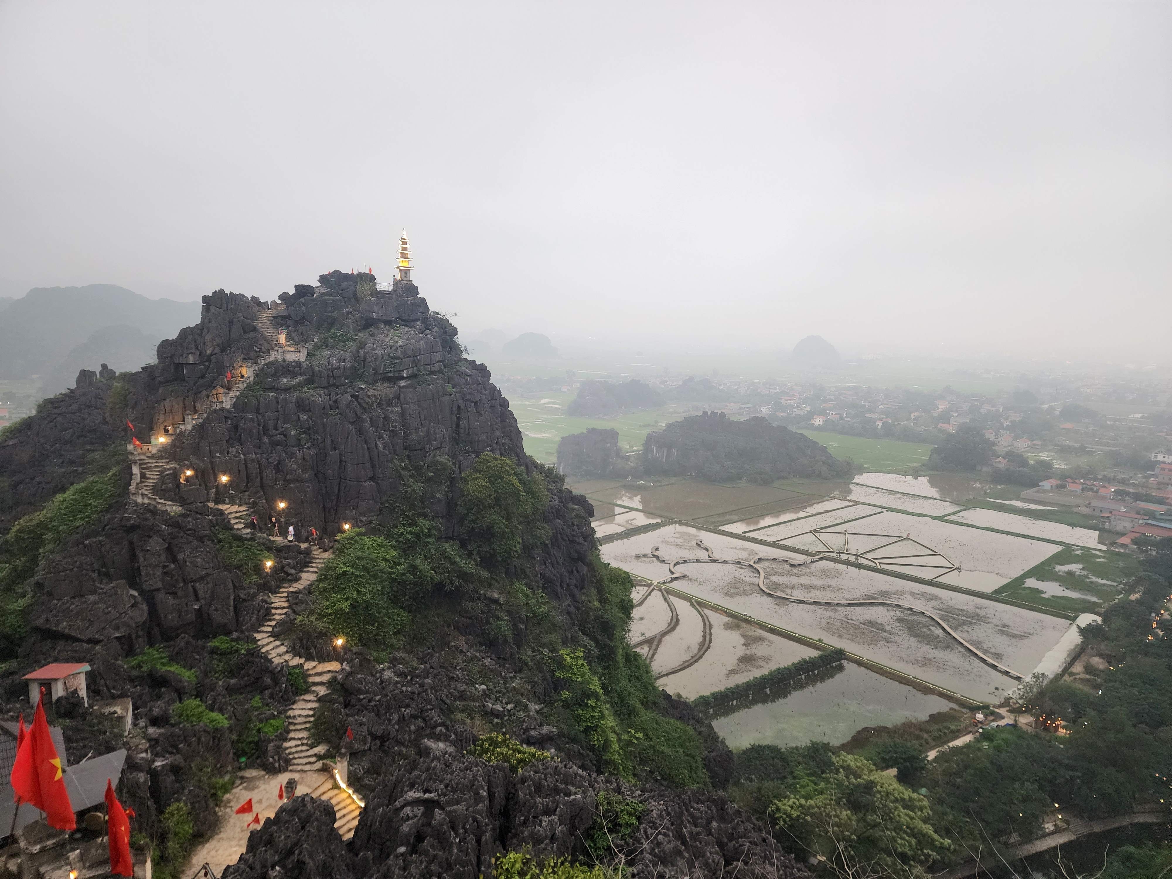 A view of flooded rice fields and limestone mountains with stairway zigzagging through at Mua Cave in Ninh Binh